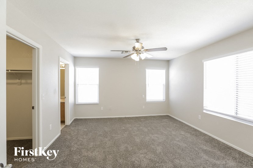 an empty living room with a ceiling fan and a closet