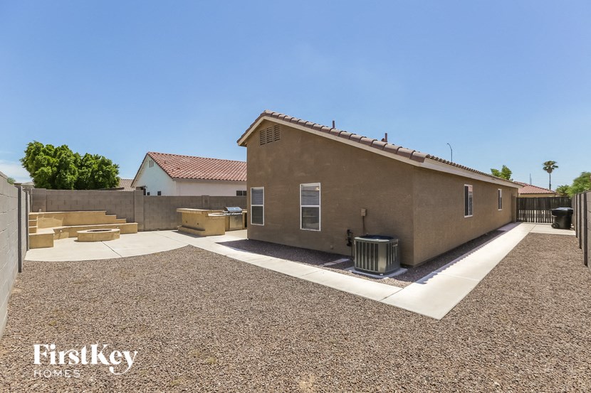 a backyard with a house and a driveway and a trash can