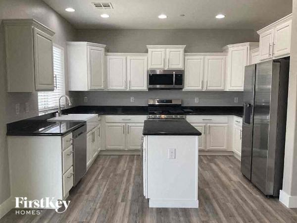 a large kitchen with white cabinets and black counter tops