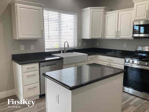 a kitchen with white cabinets and black counter tops