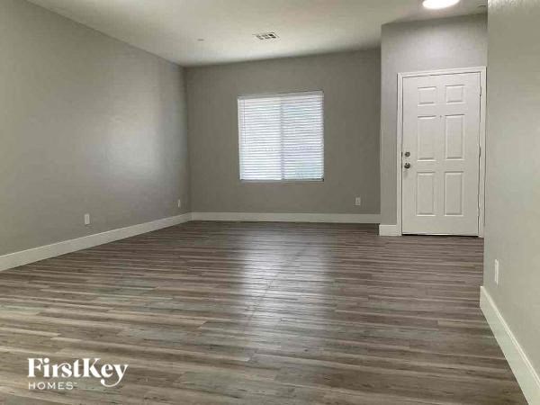 an empty living room with wood floors and a white door