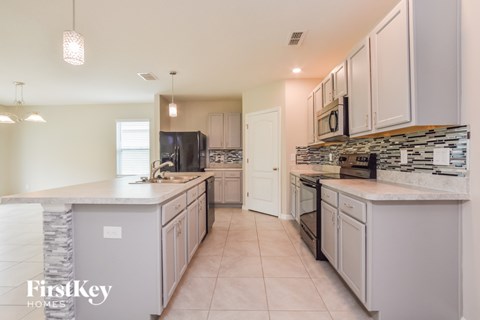 A kitchen with a black fridge and a black and white backsplash.