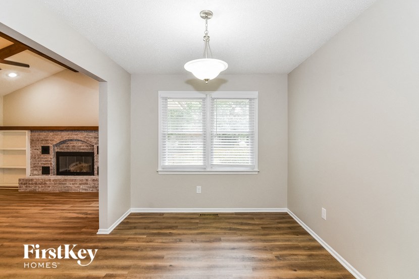 an empty living room with a fireplace and wood flooring