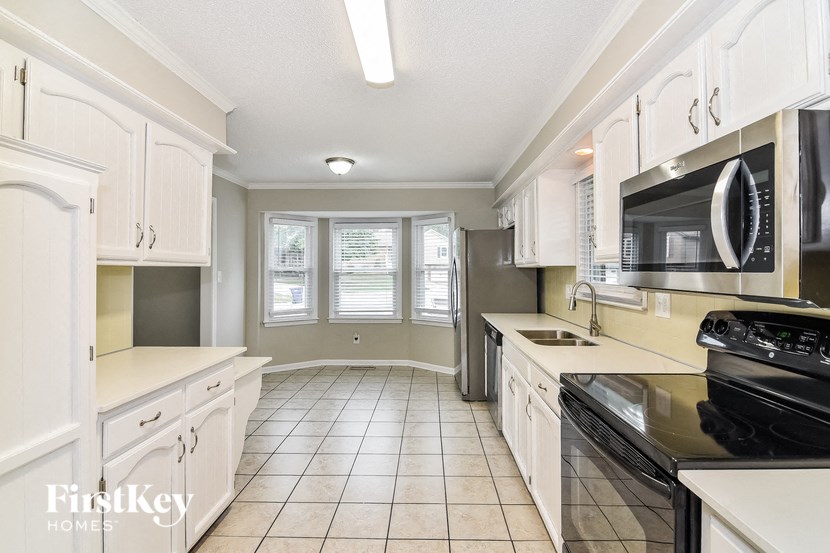 a large kitchen with white cabinets and black appliances