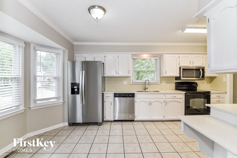 a kitchen with white cabinets and a stainless steel refrigerator