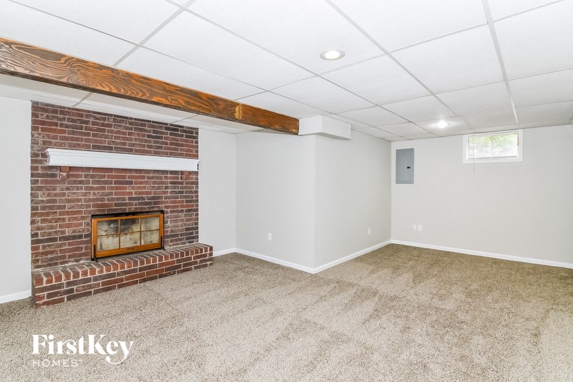 a living room with a brick fireplace and white walls