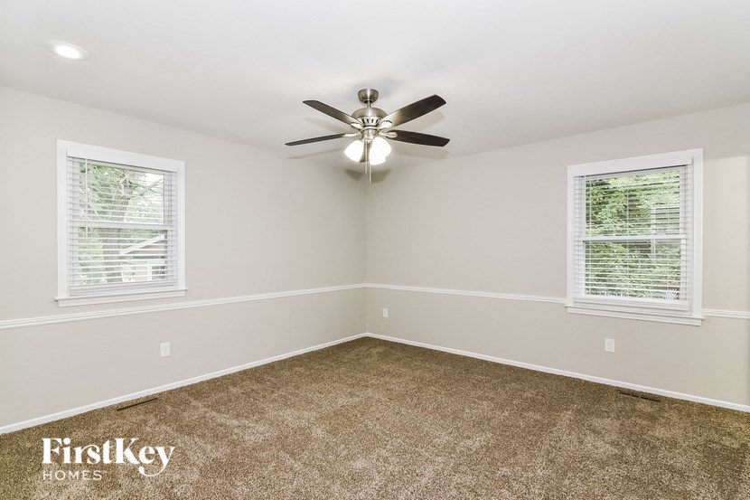 an empty room with a ceiling fan and two windows
