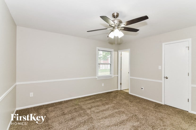 an empty living room with a ceiling fan and a door