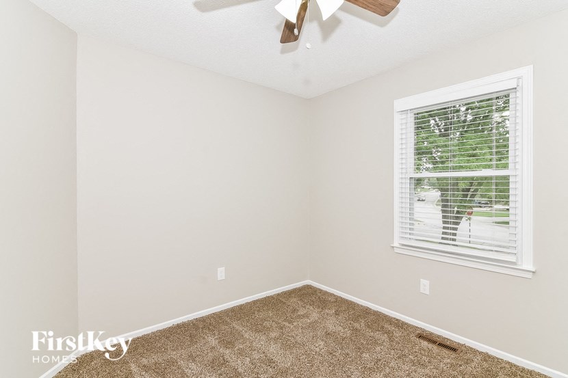 an empty bedroom with a window and a ceiling fan