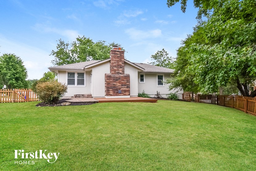 a backyard with a white house and a grass lawn