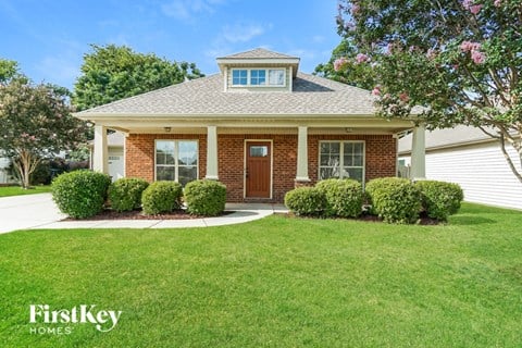 a small brick house with a front porch and a lawn