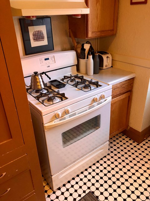 A white gas stove with a kettle on it.