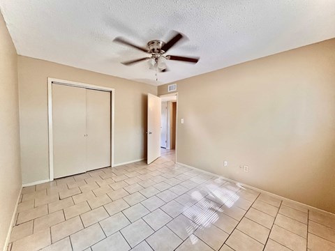 an empty living room with a ceiling fan and tiled floors