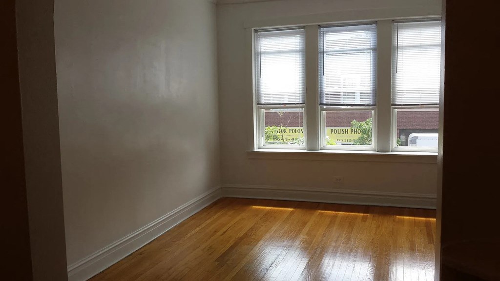 an empty room with a wood floor and three windows