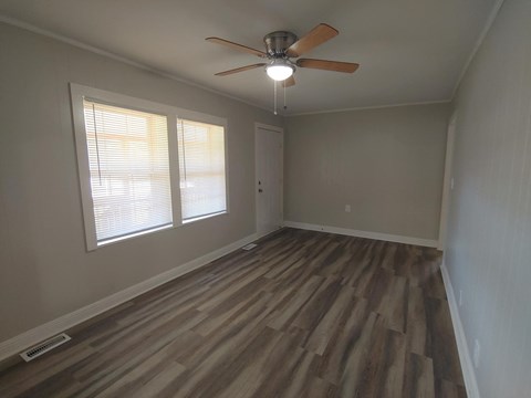 an empty living room with wood floors and a ceiling fan
