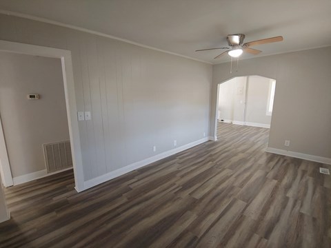 an empty living room with wooden floors and a ceiling fan