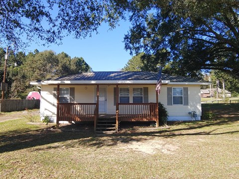 a small white house with a porch and an flag