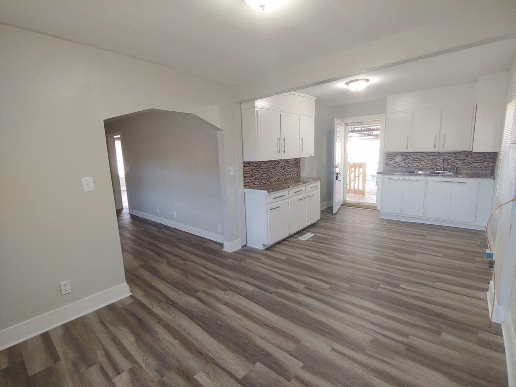 a kitchen and living room with wooden floors and white cabinets