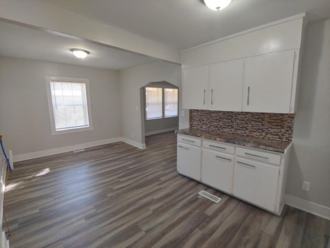 an empty kitchen with white cabinets and a counter top