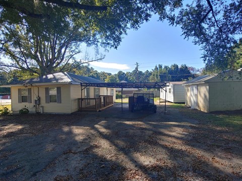 a small house with a covered porch and a dirt yard