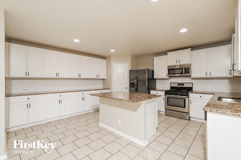 A kitchen with white cabinets and a granite countertop.