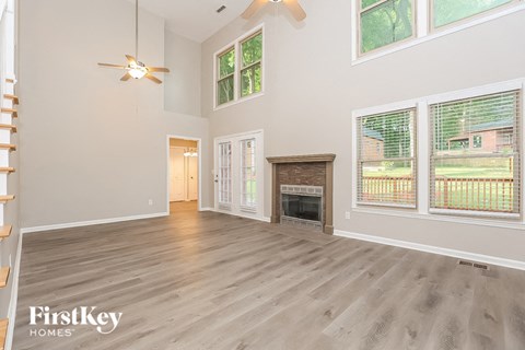 A spacious living room with a fireplace and a ceiling fan.