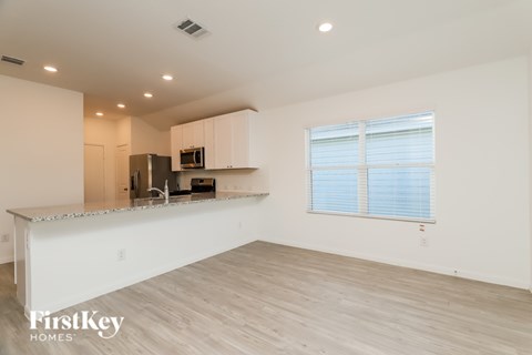 A spacious kitchen with white cabinets and a wooden floor.