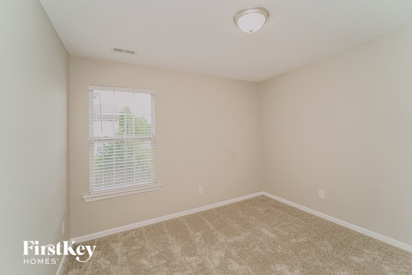 a bedroom with a large window and beige carpet