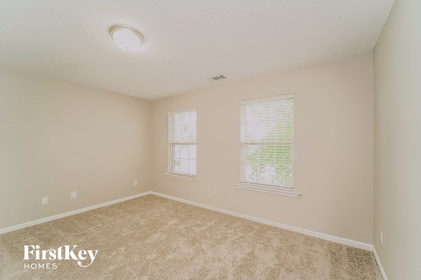 a bedroom with a carpeted floor and two windows