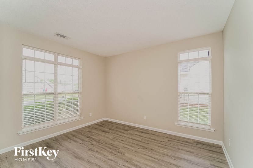 the spacious living room with wood flooring and two windows