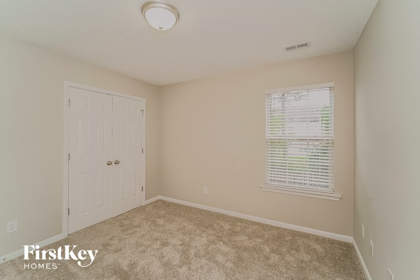 a bedroom with a white door and a window and a carpeted floor