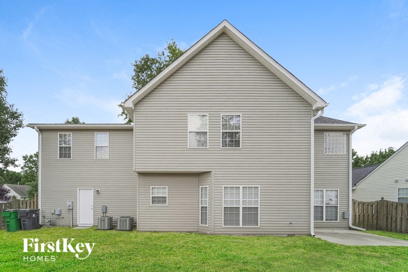 a beige house with white siding and a grassy yard