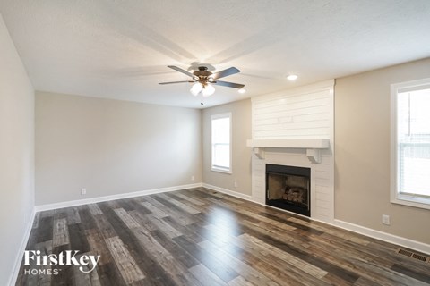 A spacious room with a fireplace and wood flooring.