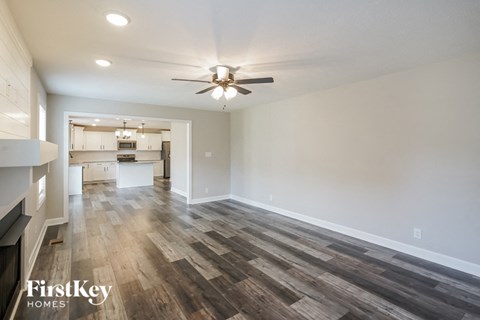 A spacious room with wooden flooring and a ceiling fan.