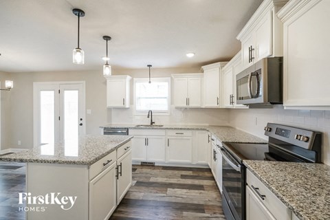 A kitchen with a granite countertop and a stove top oven.