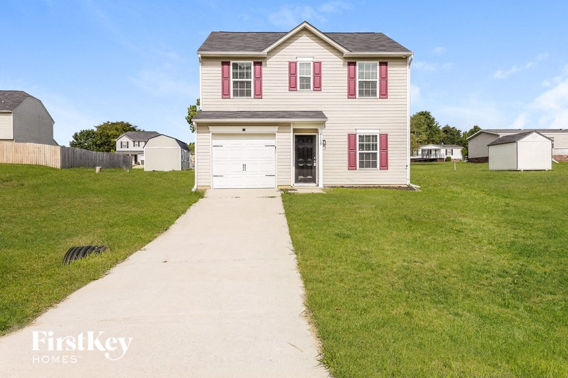 a white house with red shuttered windows and a sidewalk in front of a yard
