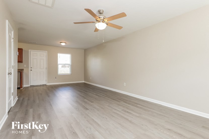 the spacious living room with hardwood flooring and a ceiling fan