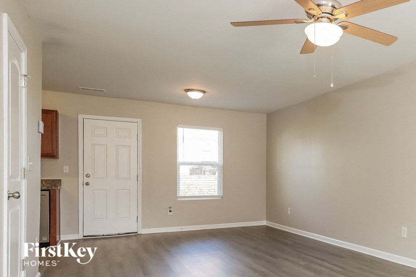 an empty living room with a ceiling fan and a white door