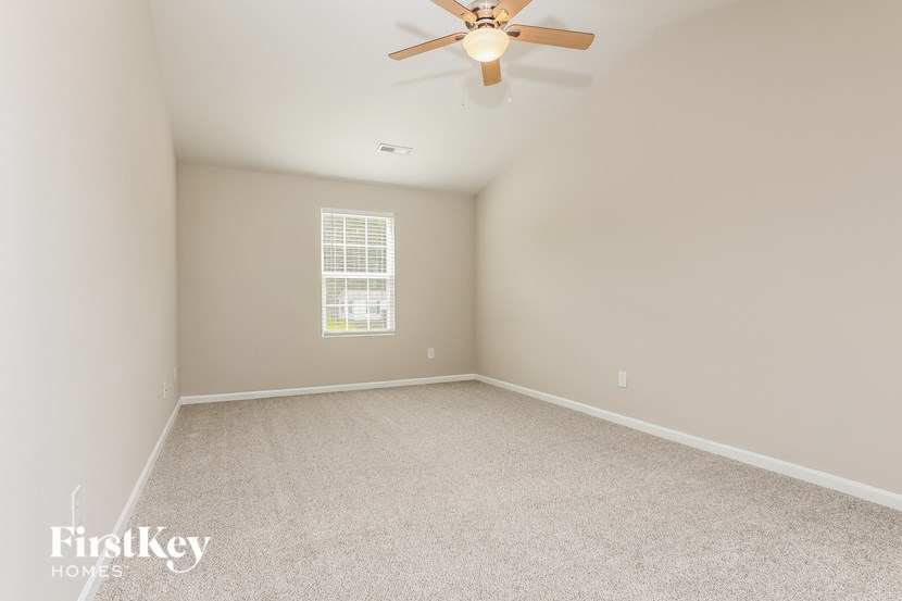 a bedroom with white carpet and a ceiling fan