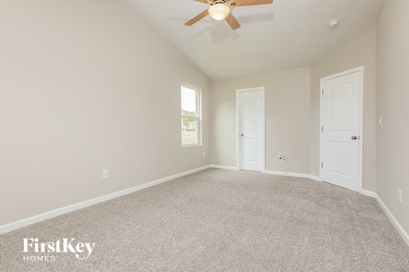 a empty living room with a ceiling fan and a white door
