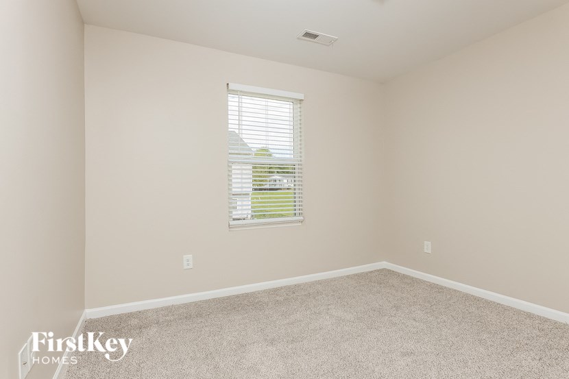 a spacious bedroom with carpet and a window