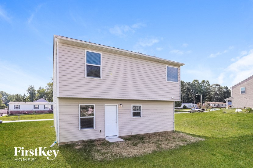 the outside of a small white house with a white garage and a lawn