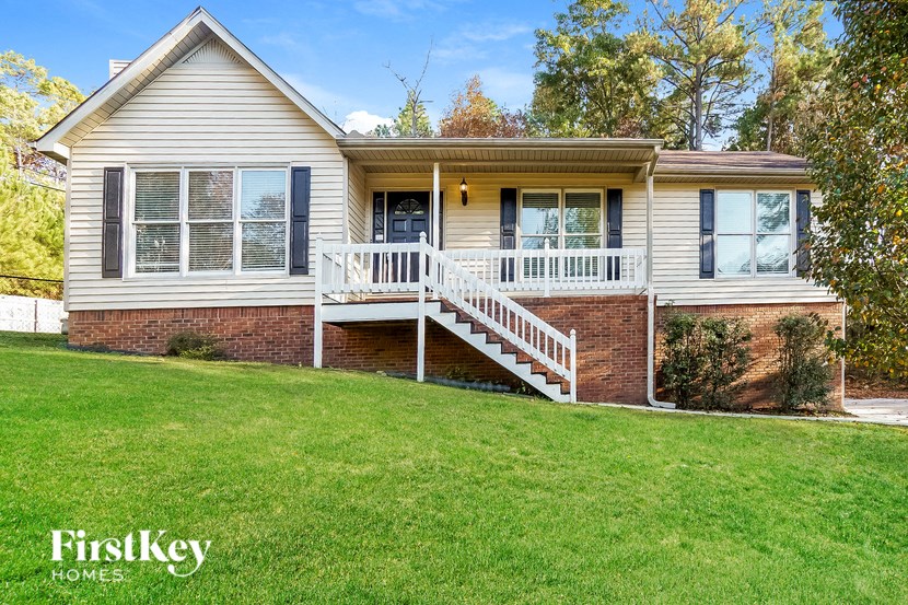 A house with a white porch and a brick foundation is for sale.