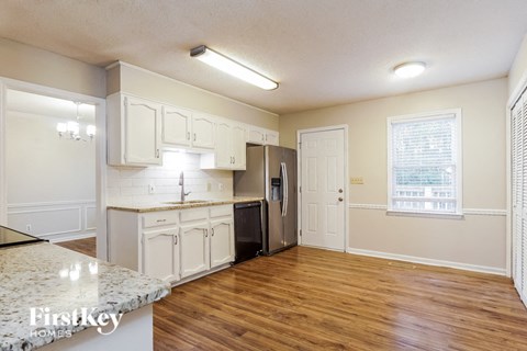 A kitchen with white cabinets and a marble countertop.