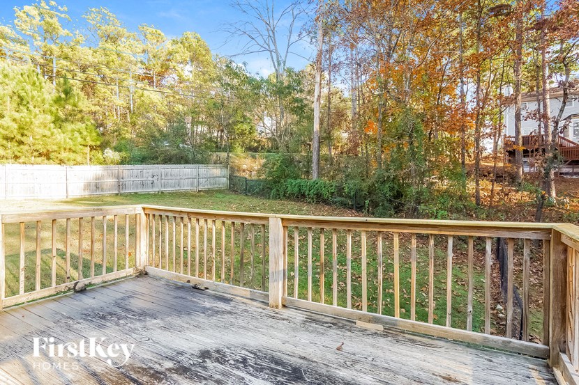 A wooden deck with a railing and trees in the background.
