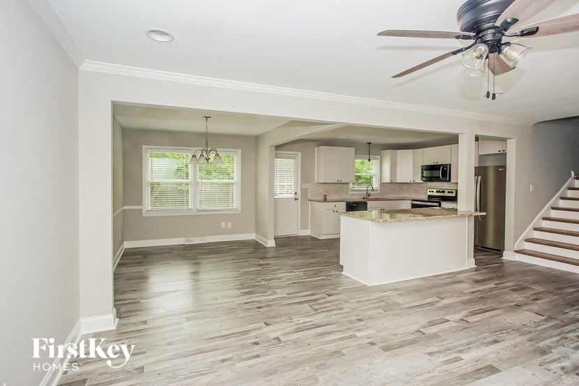 a living room with a kitchen and a ceiling fan
