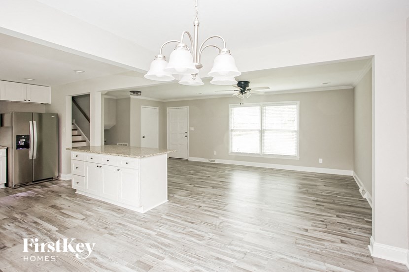 an empty kitchen and living room with a refrigerator and a sink