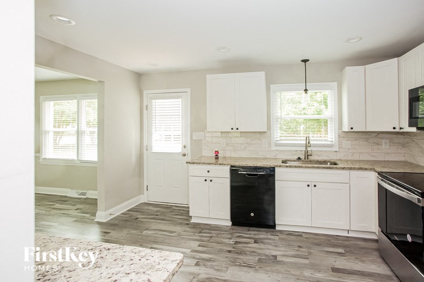 a white kitchen with black appliances and white cabinets