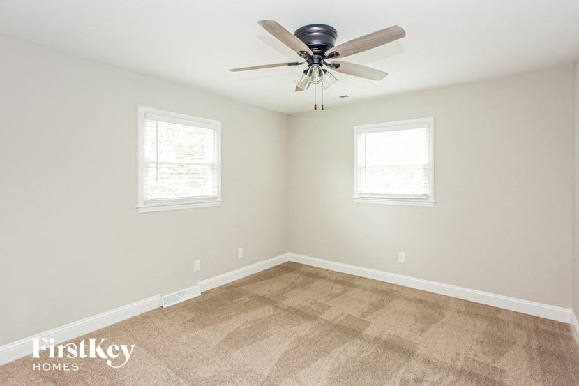 a empty room with a ceiling fan and two windows