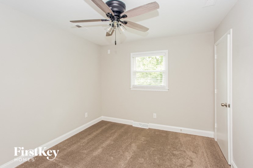 a carpeted room with a ceiling fan and a window